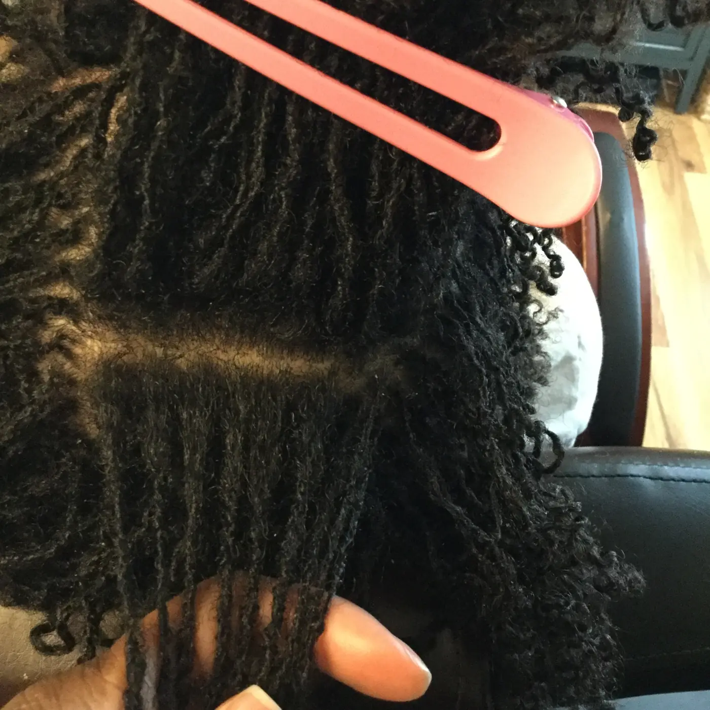 Close-up of sectioned Sisterlocks during a repair service with a pink hair clip